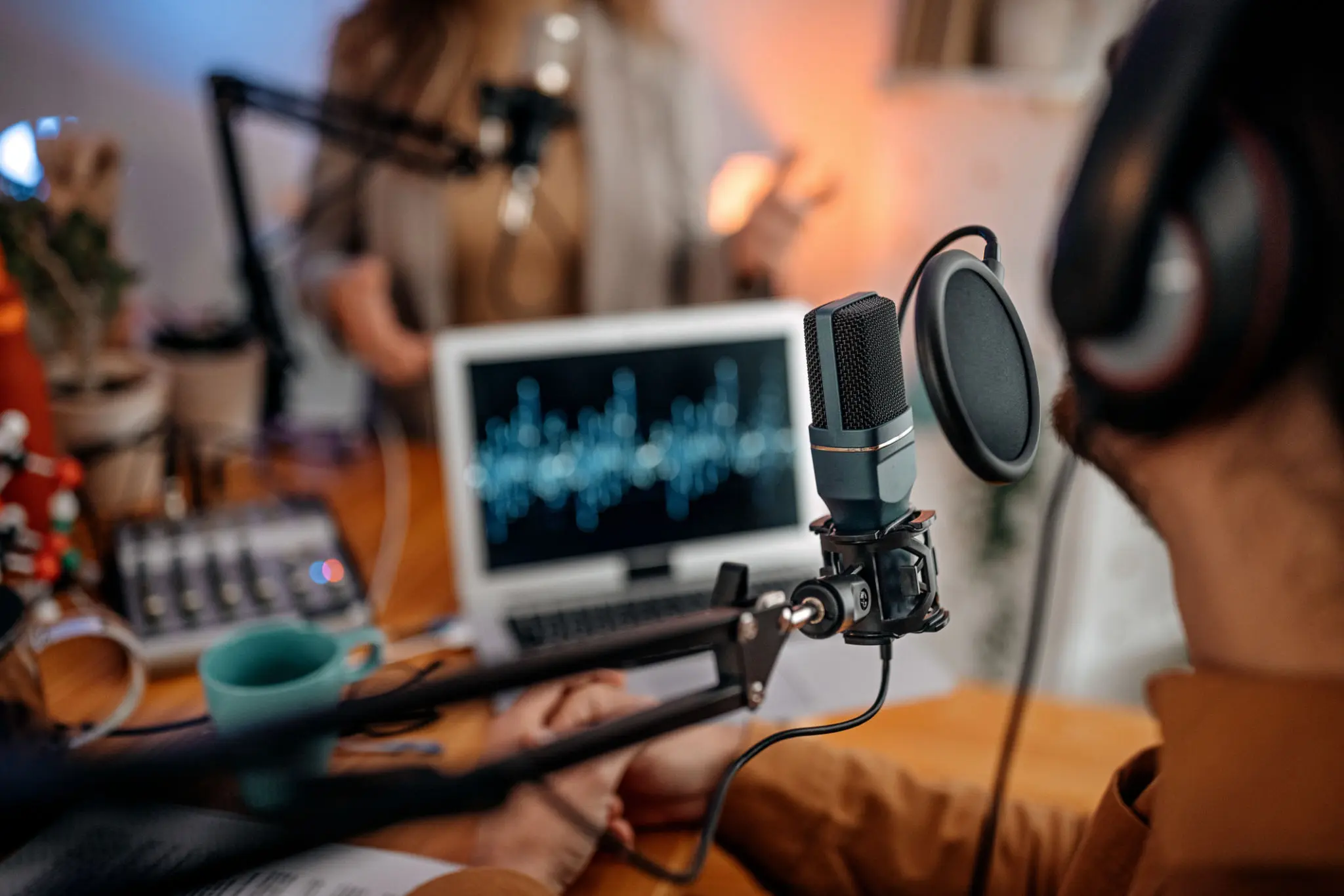 Podcast recording with microphones and laptop setup.